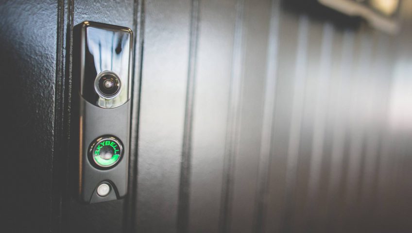 A black doorbell with a green button on it.