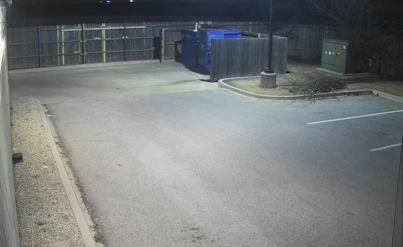 An empty parking lot at night with lights on.