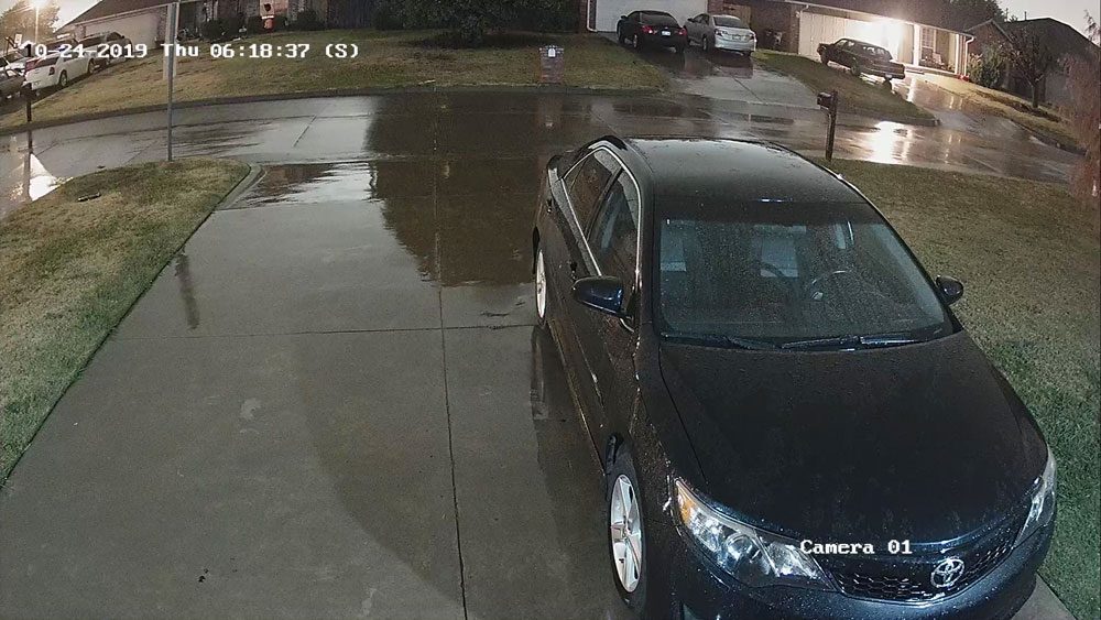 A black car is parked in the rain.