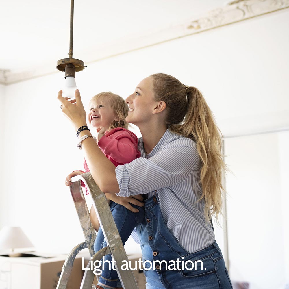 A woman and child standing on a ladder holding a light bulb.