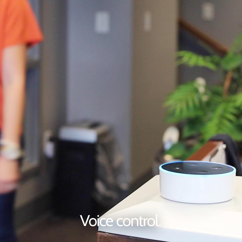 An amazon echo dot sitting on a table next to a woman.