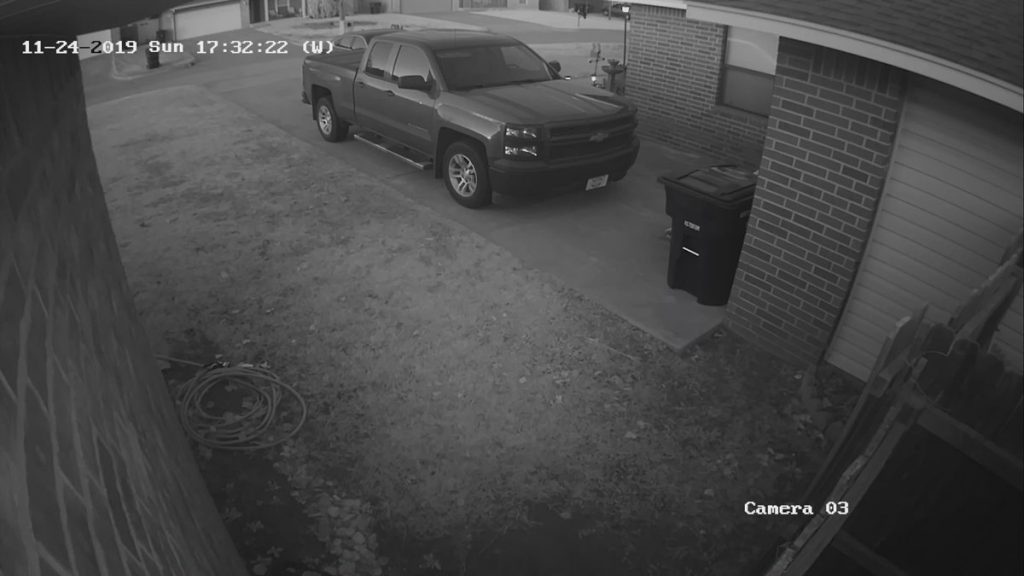 A surveillance camera shows a truck parked in a driveway.