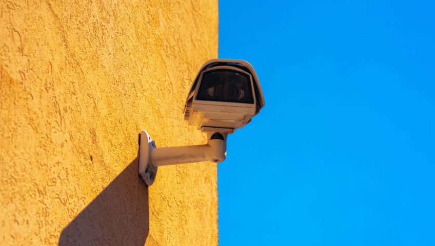 A CCTV device mounted on a yellow wall